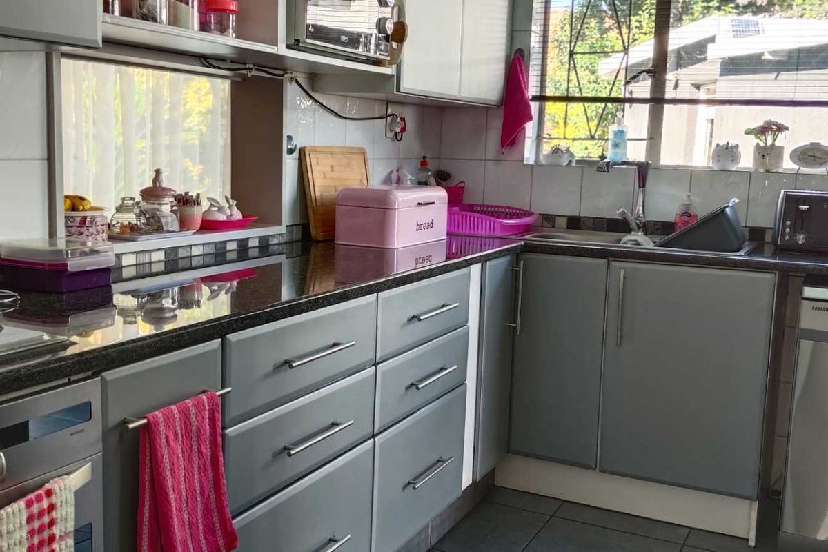 Functional kitchen featuring granite countertops, grey cabinetry, stainless steel integrated oven, and a stainless steel dishwasher.