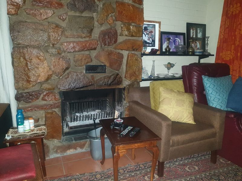 A cozy living room featuring a prominent natural stone fireplace and built-in shelving, finished with tiled flooring.
