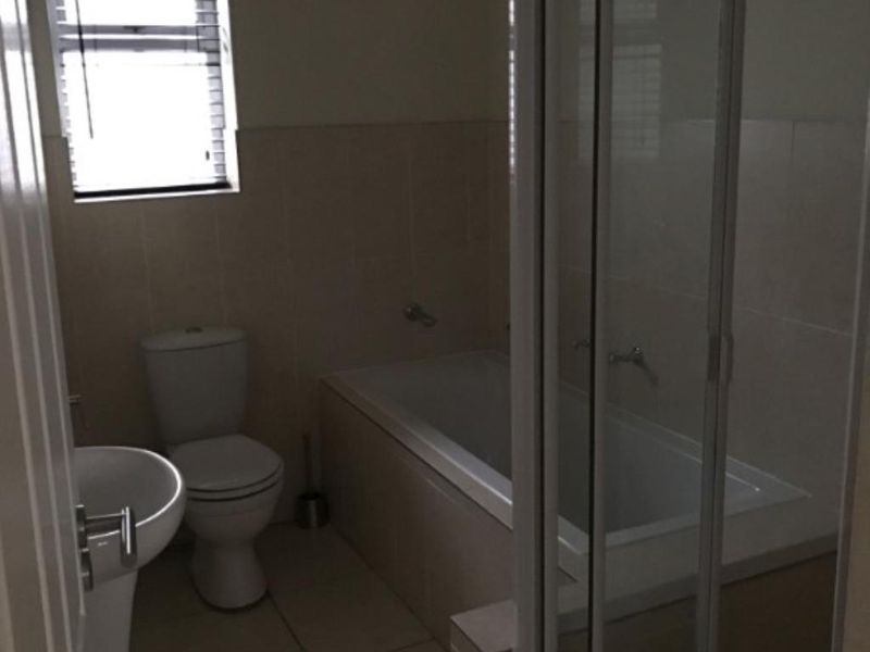 A functional bathroom featuring a pedestal basin, toilet, built-in bathtub, and a separate shower enclosure with tiled finishes throughout.