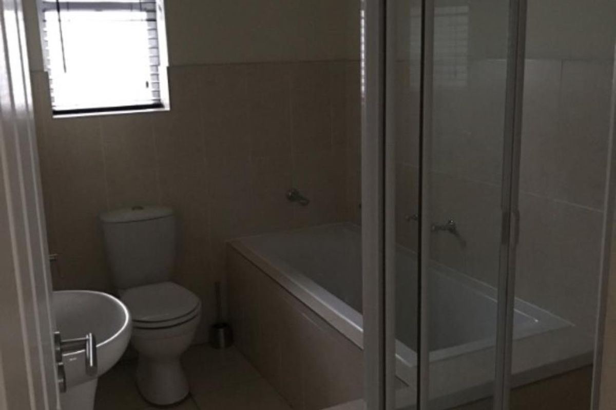 A functional bathroom featuring a pedestal basin, toilet, built-in bathtub, and a separate shower enclosure with tiled finishes throughout.