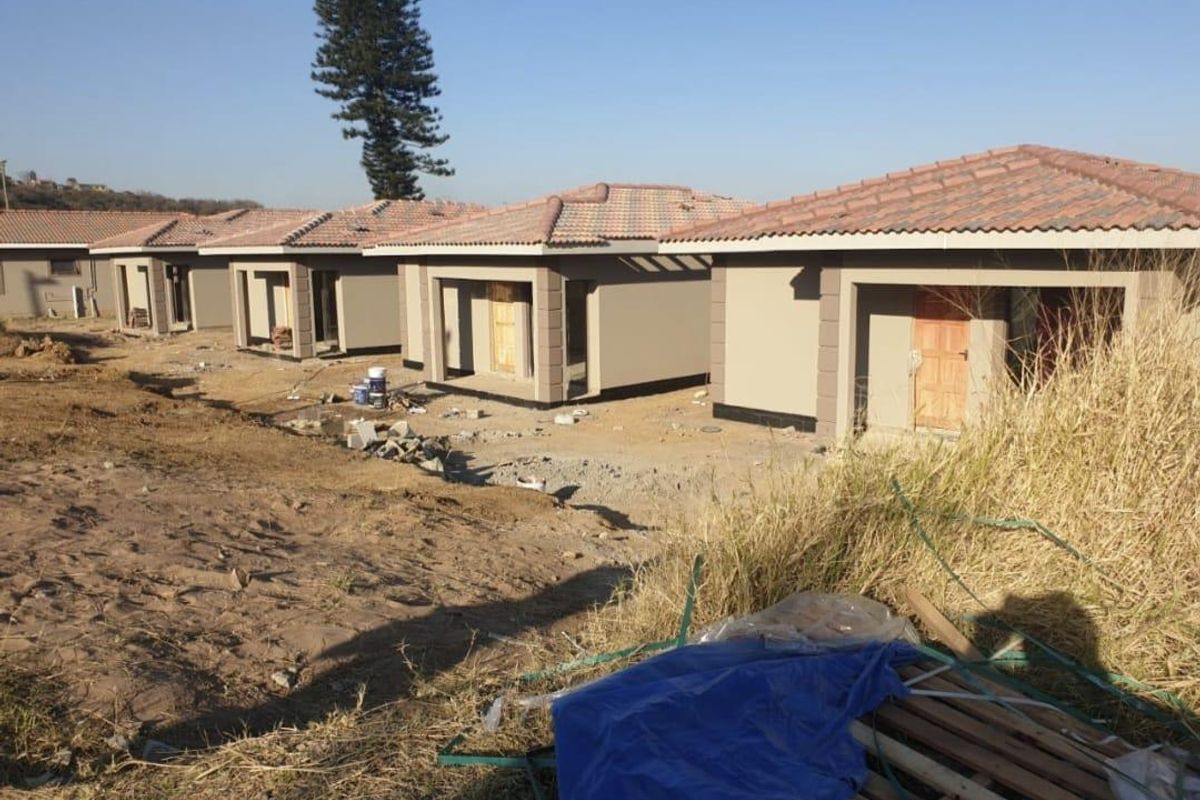 A row of newly constructed residential units featuring tiled roofs and plastered facades, currently undergoing final exterior site development.