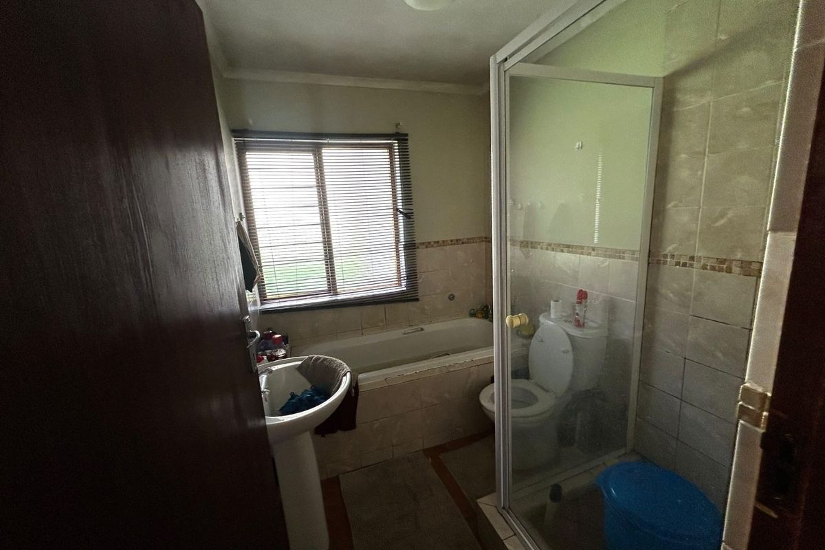 A functional bathroom featuring a pedestal basin, built-in bathtub, separate shower enclosure, and toilet, with tiled finishes throughout.
