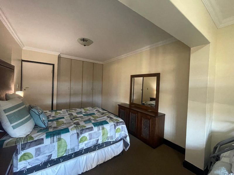 A bedroom featuring built-in cupboards, ceiling cornice detailing, and a flush mount light fixture.