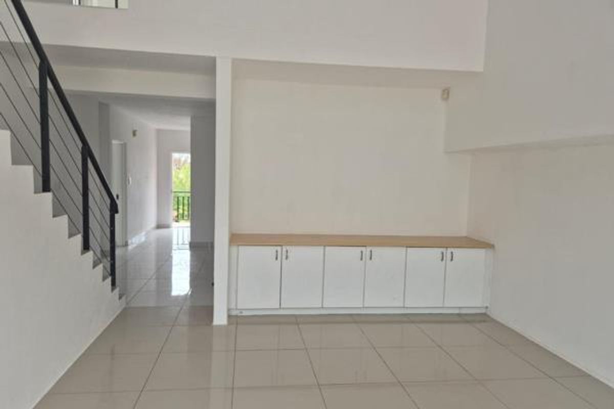 Spacious open-plan living area featuring tiled flooring, a modern staircase with metal balustrade, and built-in storage cabinetry.