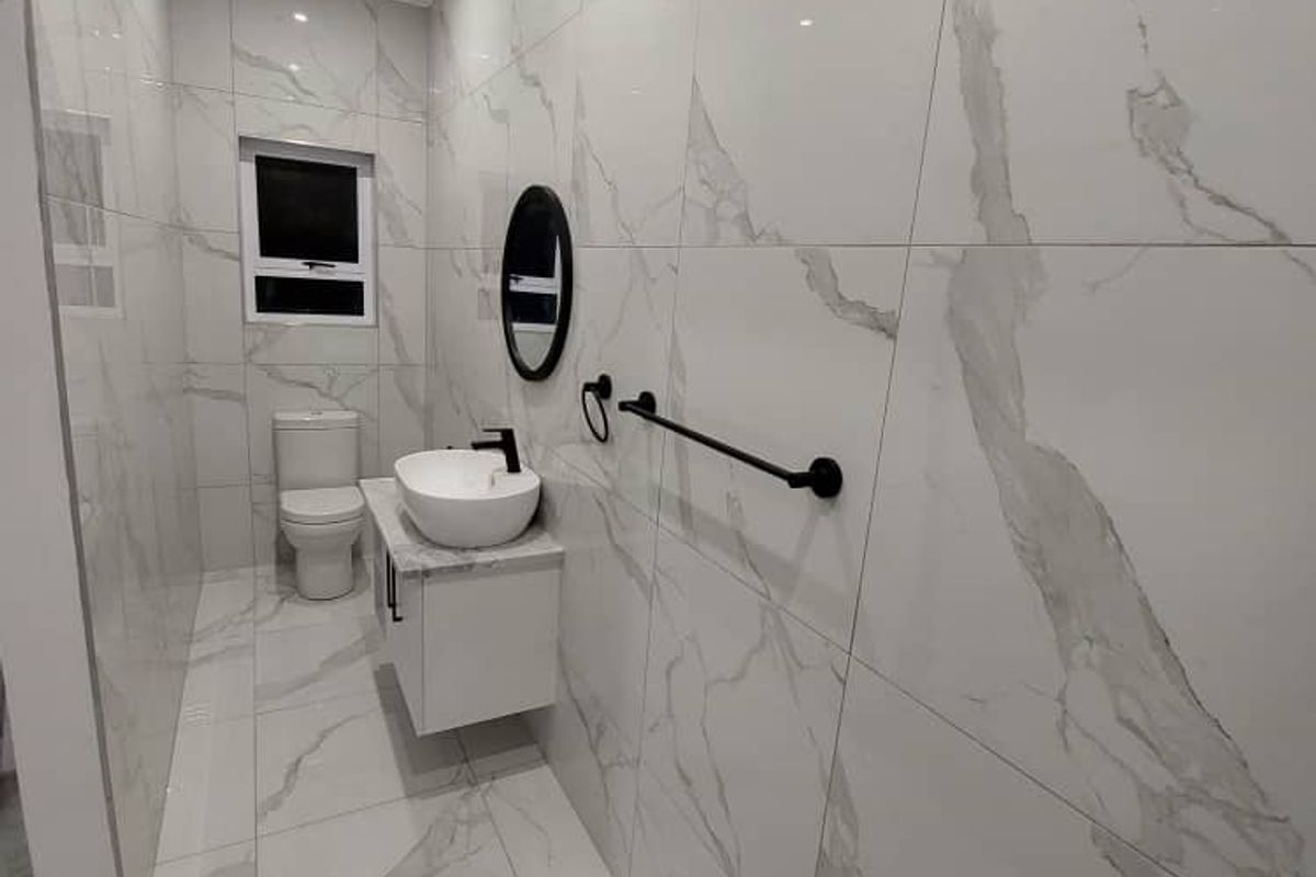 Modern bathroom featuring floor-to-ceiling marble-look porcelain tiles, a sleek vanity with vessel sink, and contemporary black fixtures.