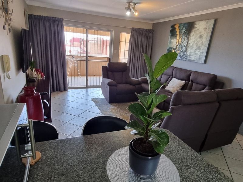 Open plan living area featuring tiled flooring, a granite breakfast bar, and a sliding glass door leading to a balcony.