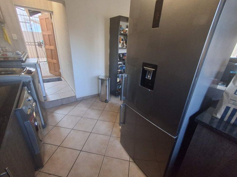 A functional laundry area featuring tiled flooring and direct access to the exterior through a secure door.