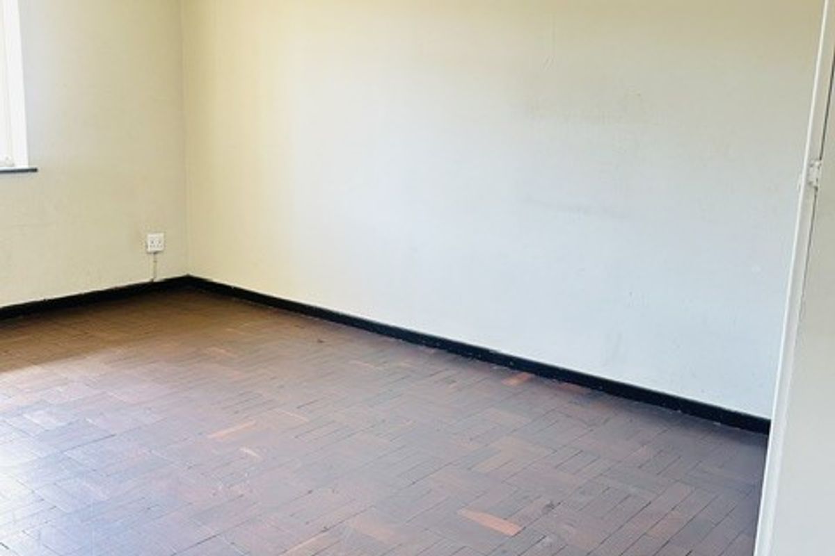 An empty bedroom featuring traditional parquet flooring and neutral wall finishes, offering a blank canvas for renovation or interior design.