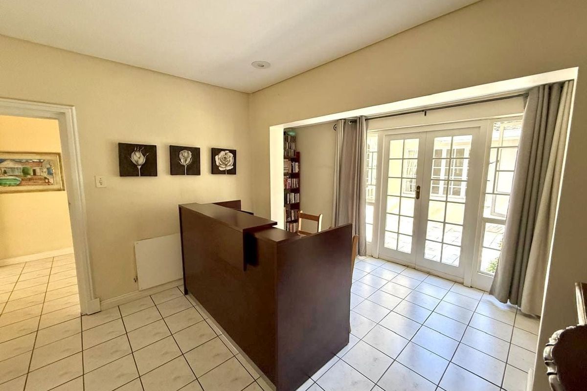 A bright living area featuring ceramic floor tiles, recessed ceiling lighting, and double glass doors providing direct access to the outdoor space.