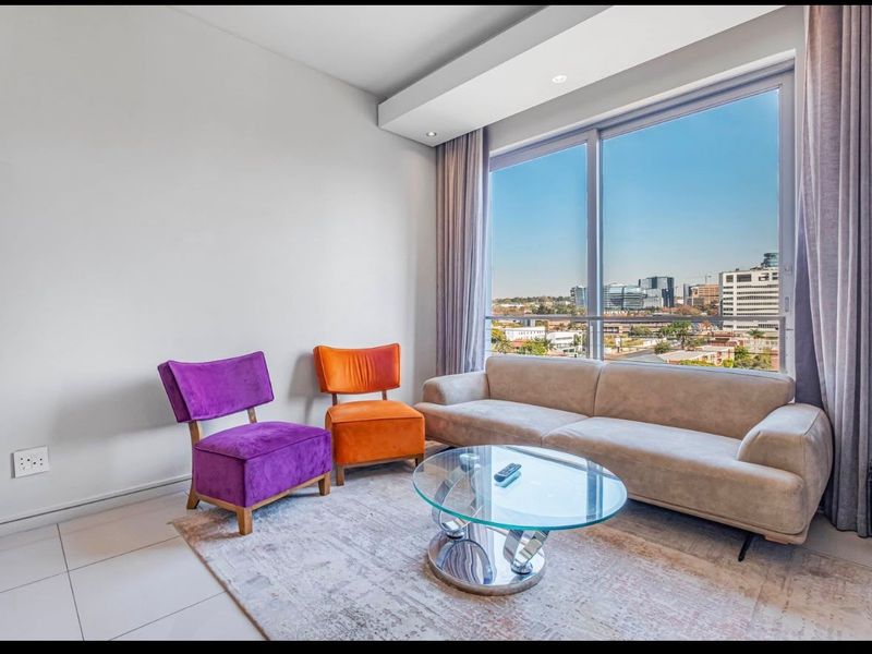 A bright living room featuring large floor-to-ceiling windows with expansive city views, recessed ceiling lighting, and neutral tiled flooring.