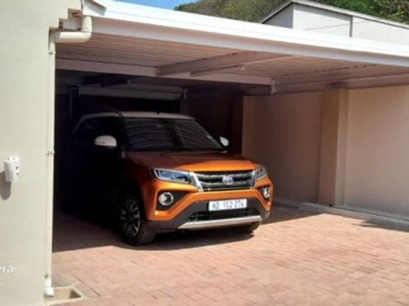 A covered carport area with paved flooring and secure gated access.