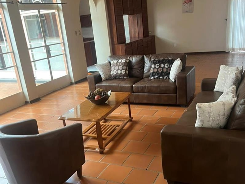 Spacious living area featuring terracotta floor tiles, built-in wooden cabinetry, and large glass doors providing natural light and access to the exterior.