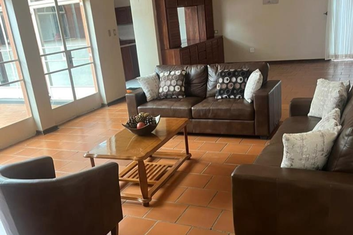 Spacious living area featuring terracotta floor tiles, built-in wooden cabinetry, and large glass doors providing natural light and access to the exterior.