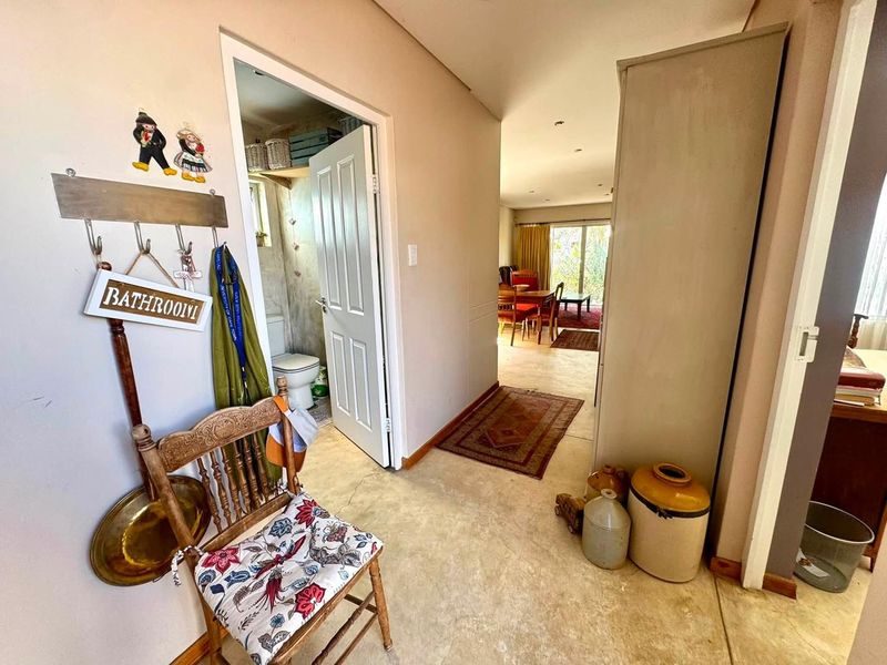 A functional hallway featuring polished concrete flooring, providing access to the bathroom and the open-plan living area beyond.