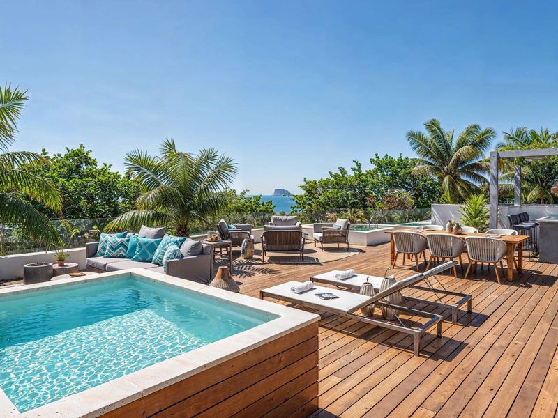 Spacious outdoor terrace featuring a private plunge pool, timber decking, glass balustrades, and scenic ocean views, perfect for outdoor entertaining.