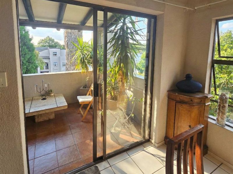 A covered balcony featuring tiled flooring, a concrete balustrade, and sliding glass doors, offering an outdoor space connected to the interior living area.