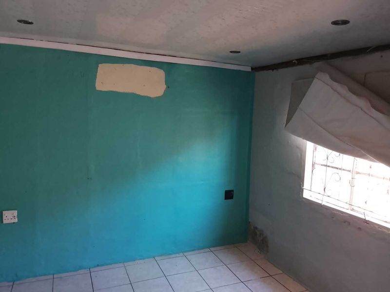 An empty bedroom featuring tiled flooring and recessed lighting, currently requiring significant cosmetic repairs to the walls and ceiling finishes.
