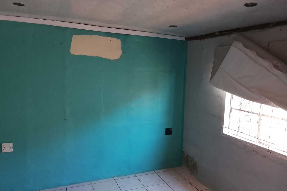An empty bedroom featuring tiled flooring and recessed lighting, currently requiring significant cosmetic repairs to the walls and ceiling finishes.