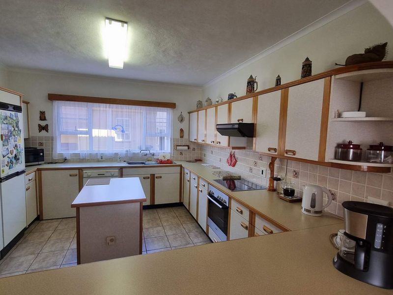 A functional kitchen featuring built-in cabinetry, a central island, ceramic tile backsplash, and integrated appliances, offering a classic layout with potential for modern updates.