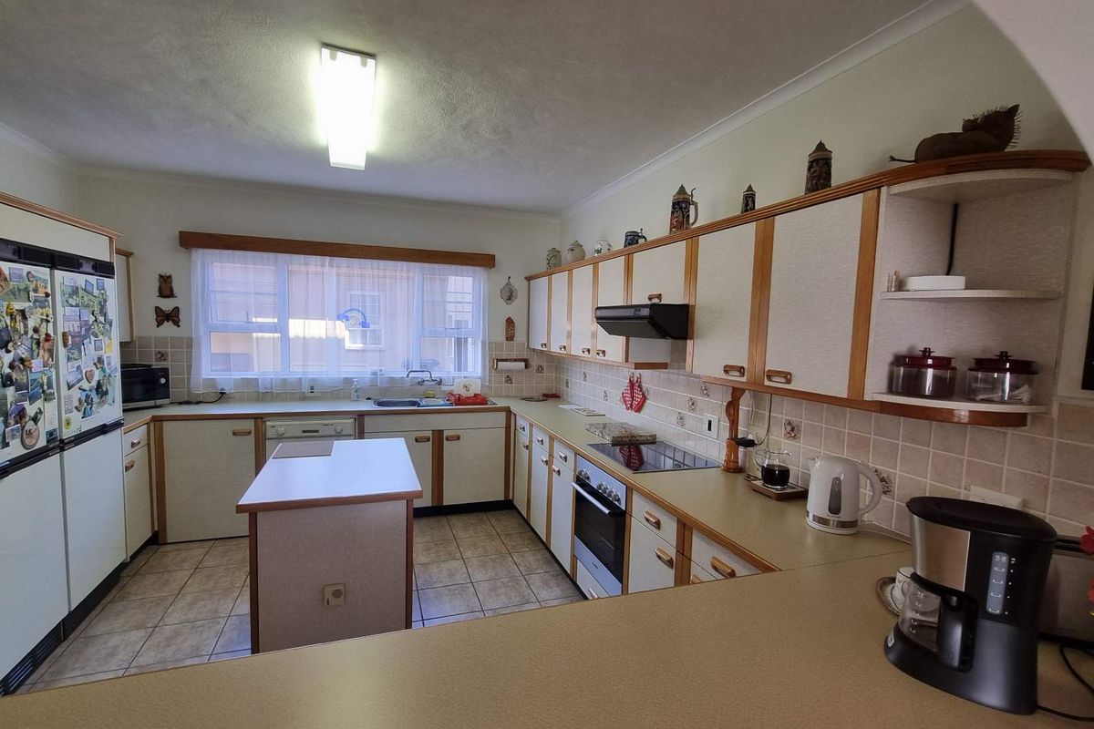 A functional kitchen featuring built-in cabinetry, a central island, ceramic tile backsplash, and integrated appliances, offering a classic layout with potential for modern updates.