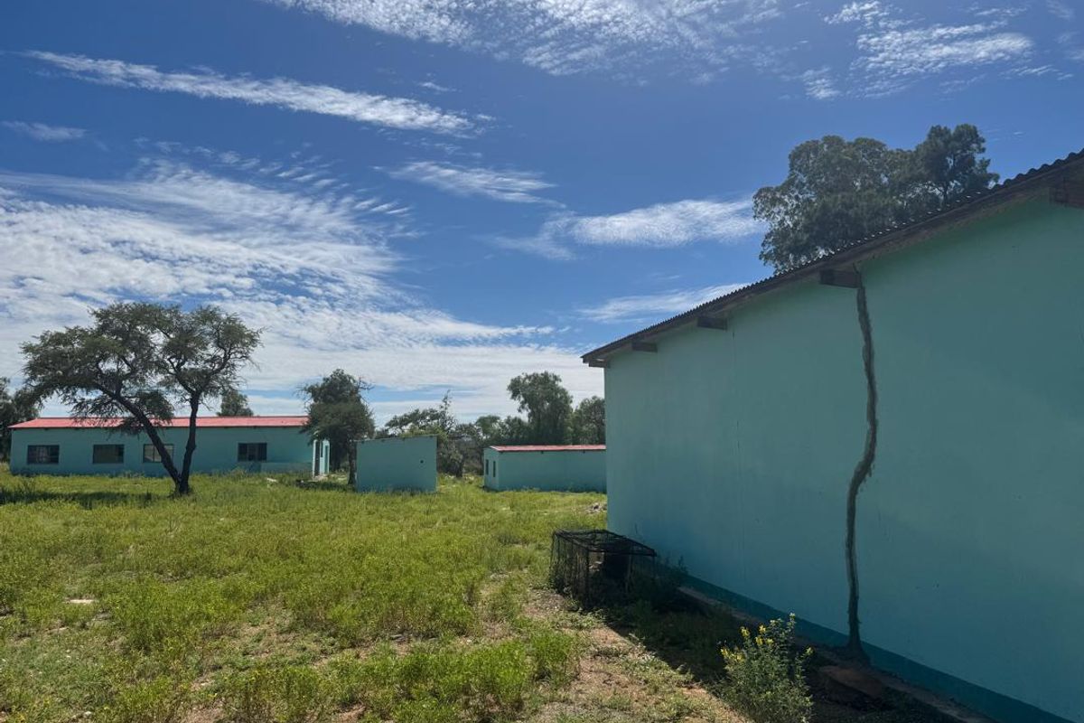Exterior view of farm outbuildings showing significant structural cracking on the side wall of the primary structure.