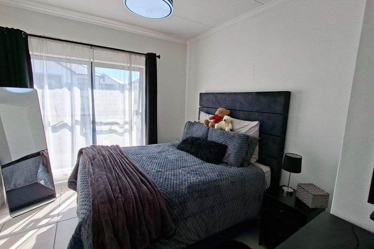 A well-lit bedroom featuring tiled flooring, a sliding glass door providing natural light, and decorative cove cornicing.