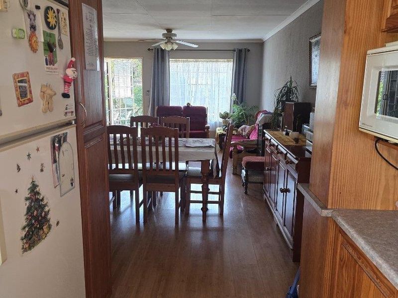 Open-plan living and dining area featuring laminate flooring, wooden cabinetry, and a ceiling fan, providing a functional and connected layout.