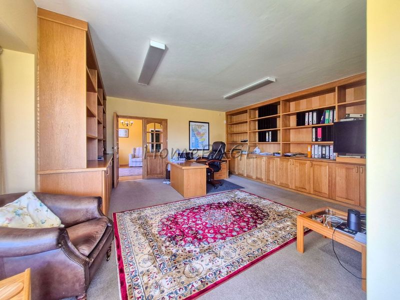 A spacious home office featuring extensive built-in wooden cabinetry and shelving, providing ample storage and workspace in a functional layout.