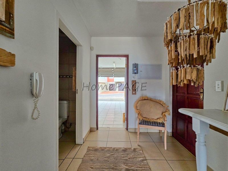 Entrance foyer featuring tiled flooring, an intercom system, and direct access to a guest bathroom and the exterior.