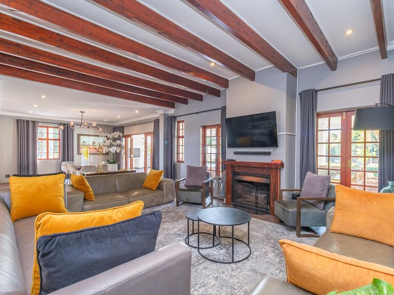 Spacious open-plan living area featuring exposed timber ceiling beams, a built-in fireplace with a timber mantel, and direct access to the outdoor area.