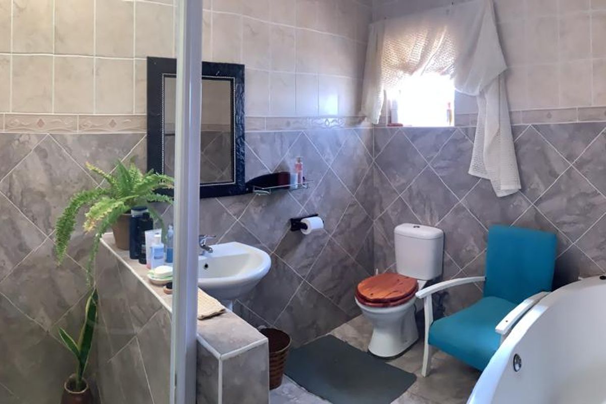 A functional bathroom featuring a corner bathtub, separate shower enclosure, pedestal basin, and toilet with neutral wall tiling.