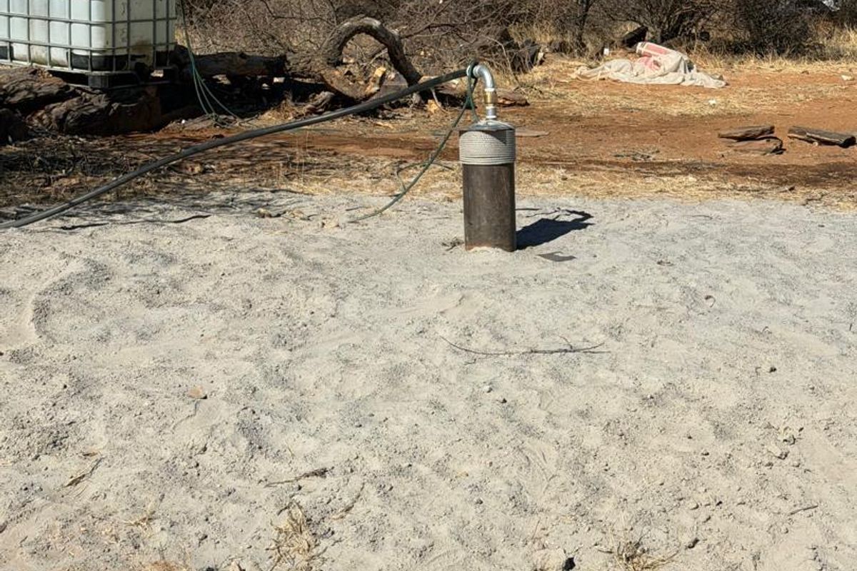 Agricultural land featuring a functional borehole with a connected water storage tank, situated in a natural, undeveloped landscape.