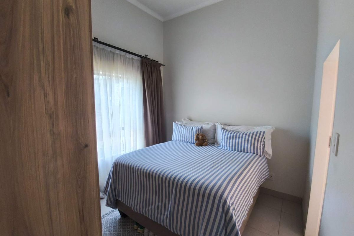 A well-maintained bedroom featuring tiled flooring, neutral wall finishes, and a built-in wooden wardrobe, offering a clean and functional living space.