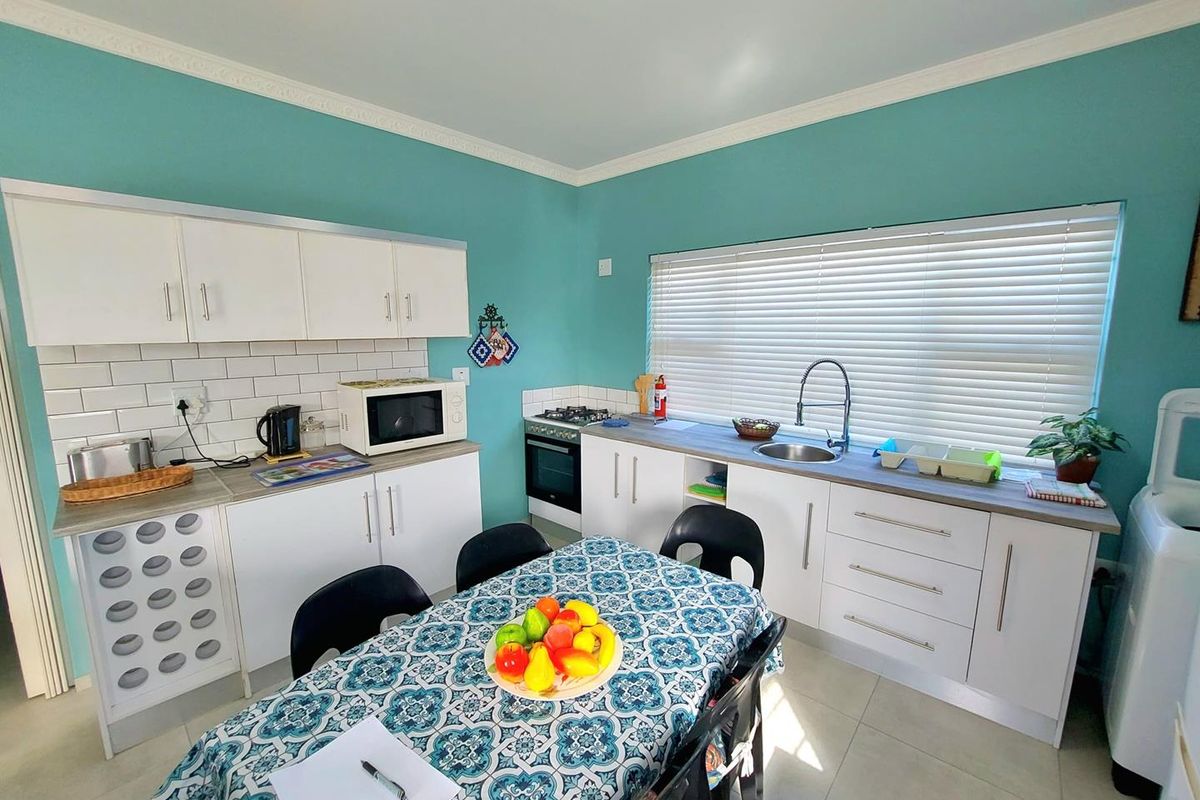 A functional kitchen featuring white cabinetry, tiled backsplash, built-in oven and hob, and a stainless steel sink with a window view.