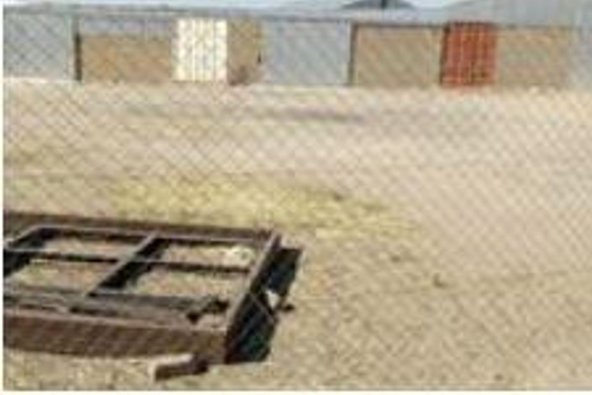 View of an industrial yard featuring metal cladding, multiple roller doors, and a chain link fence perimeter.