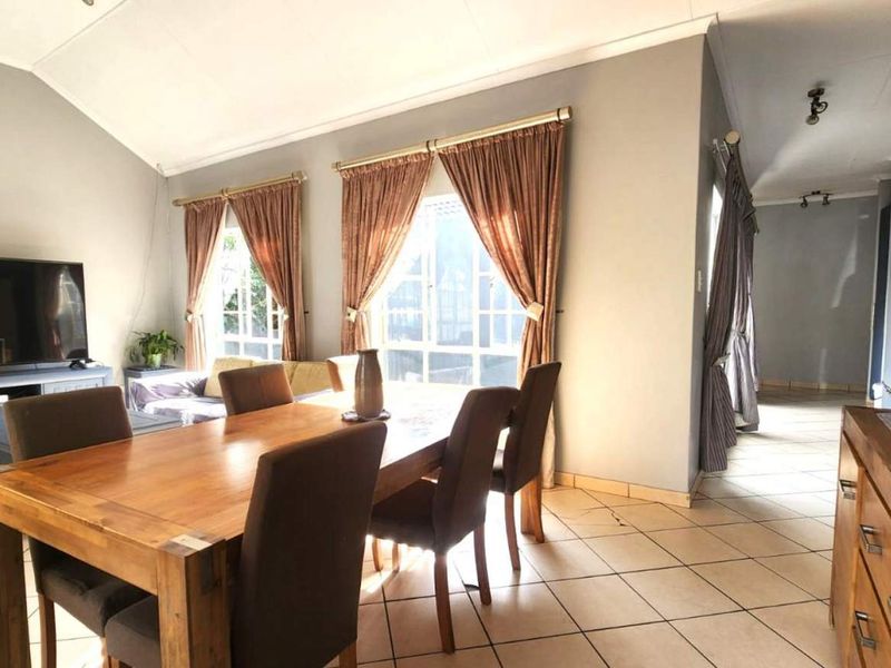 Spacious open-plan living and dining area featuring vaulted ceilings, tiled flooring, and large windows that provide ample natural light.