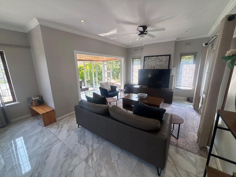 Spacious living room featuring marble-look floor tiles, a brick fireplace, and large sliding glass doors that provide seamless access to the outdoor patio area.