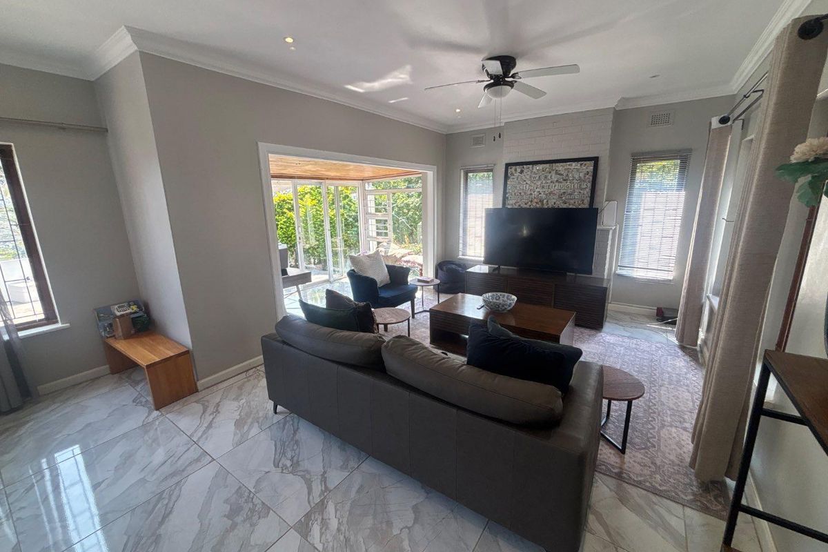 Spacious living room featuring marble-look floor tiles, a brick fireplace, and large sliding glass doors that provide seamless access to the outdoor patio area.
