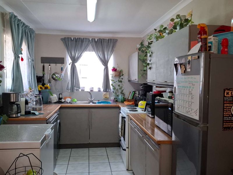 A functional kitchen featuring laminate countertops, built-in cabinetry, and tiled flooring, offering a practical layout with potential for modern cosmetic updates.