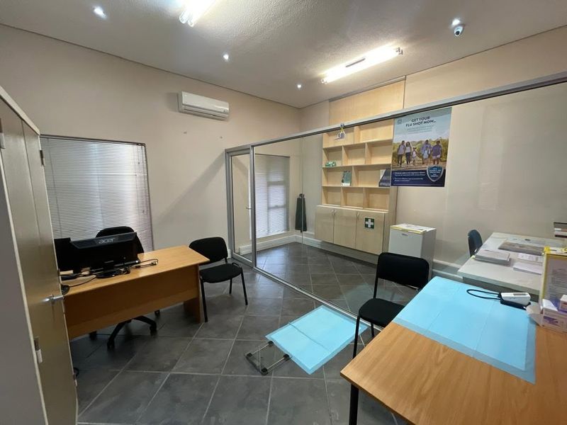 A functional office space featuring tiled flooring, built-in cabinetry, and a glass partition wall, suitable for professional or medical consultation use.