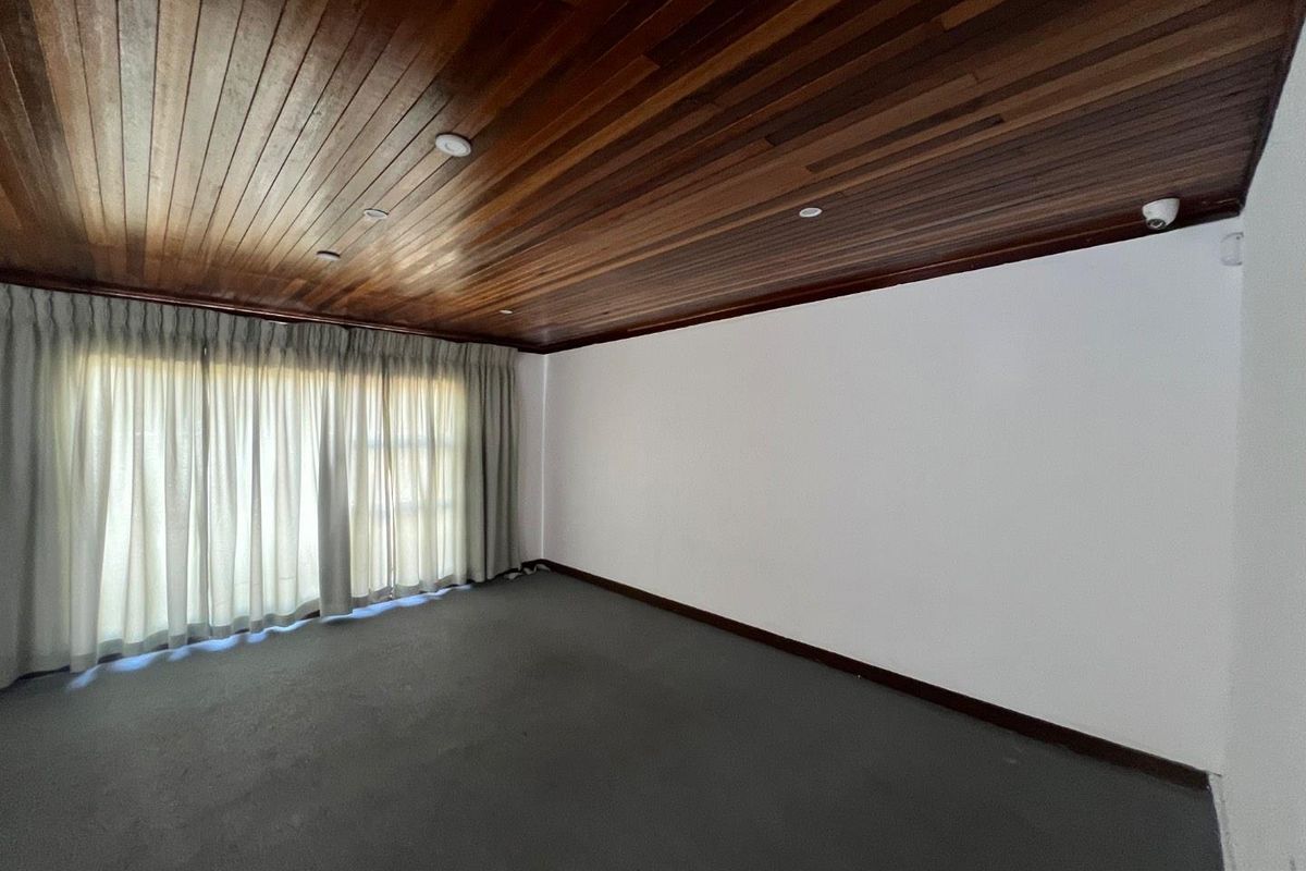 Spacious bedroom featuring a distinctive timber-paneled ceiling, recessed lighting, and large sliding glass doors with integrated curtain tracks.