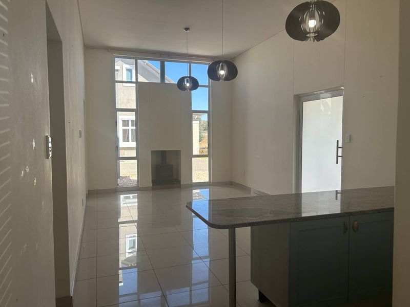 Spacious open-plan living area featuring a fireplace, large windows for natural light, and a kitchen island with granite countertops.