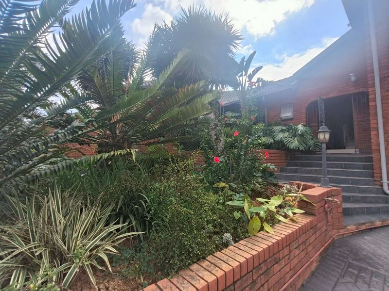 Front entrance area featuring a brick retaining wall, landscaped garden, and tiled steps leading to the main house entrance.