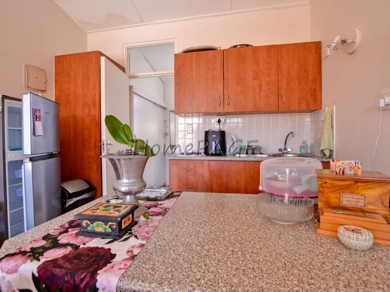 A functional kitchen featuring wood-look cabinetry, granite countertops, and a tiled backsplash, offering practical storage and workspace.