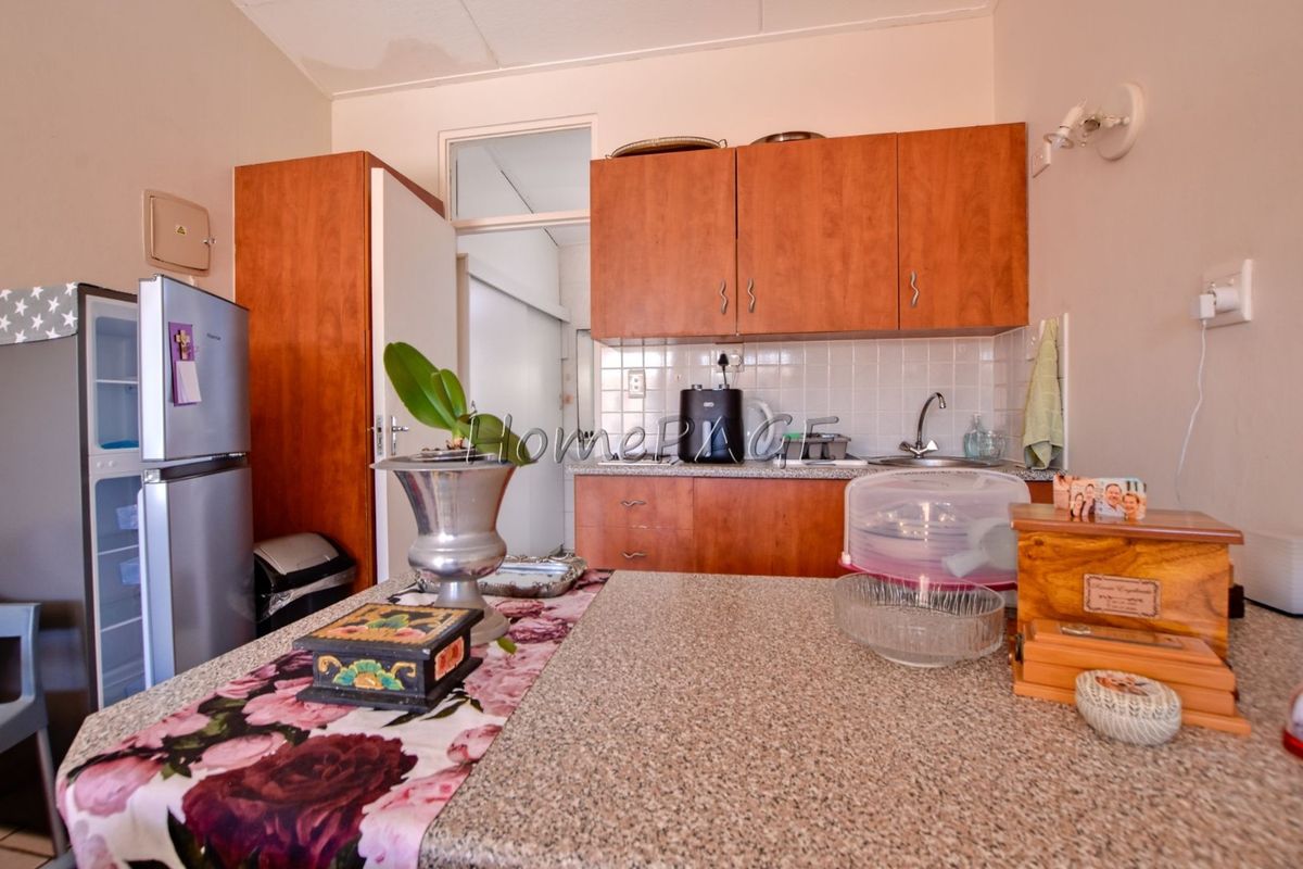 A functional kitchen featuring wood-look cabinetry, granite countertops, and a tiled backsplash, offering practical storage and workspace.