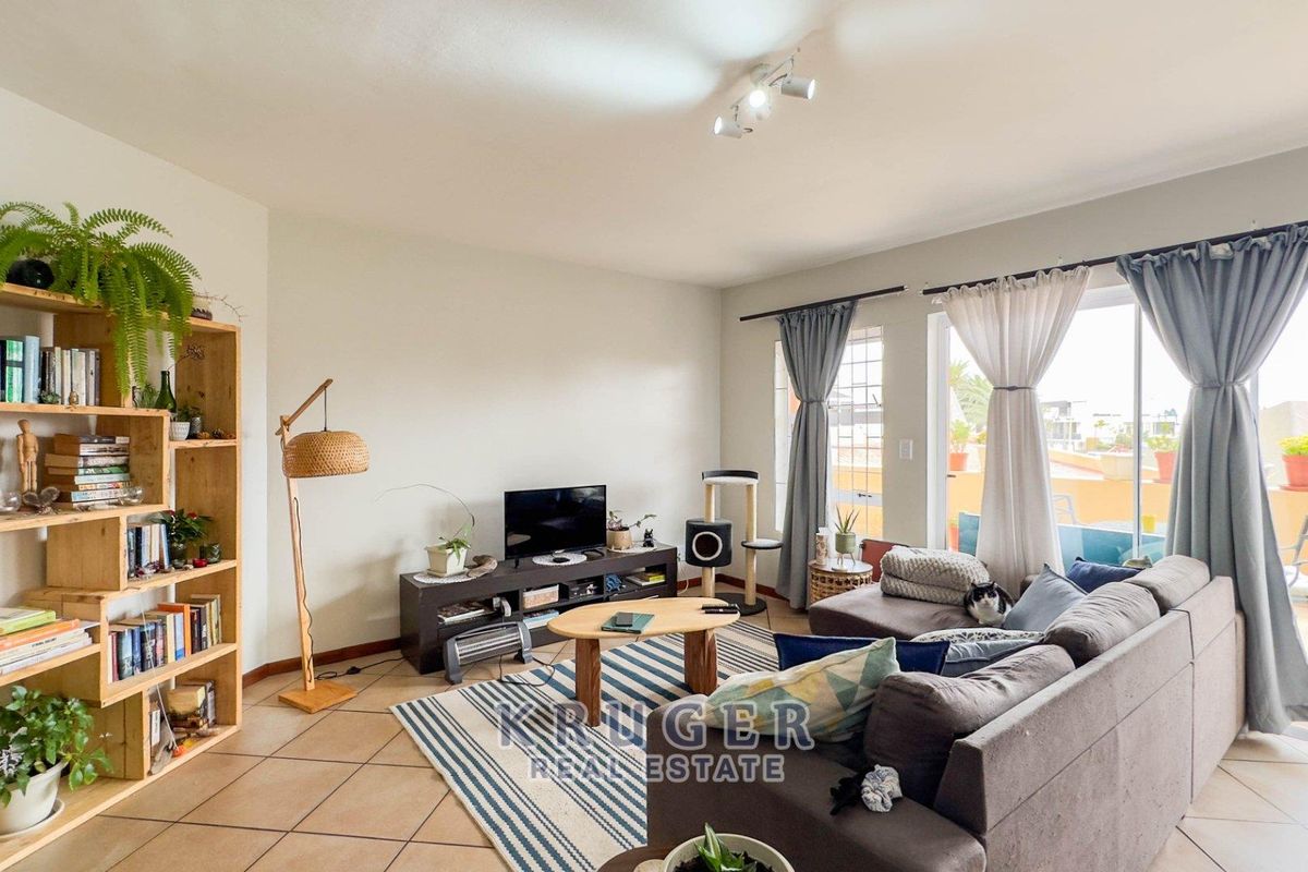 A comfortable living room featuring tiled flooring and a large sliding glass door that provides access to an outdoor balcony area.