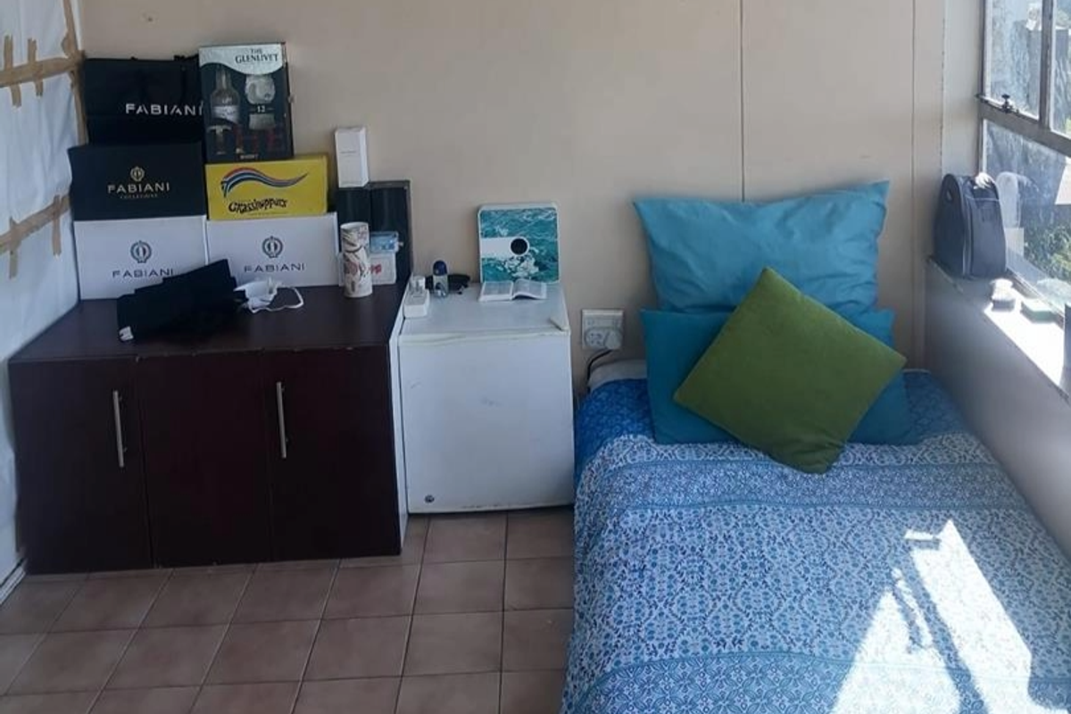 A compact bedroom featuring tiled flooring and a window, currently used as a multi-purpose living space.