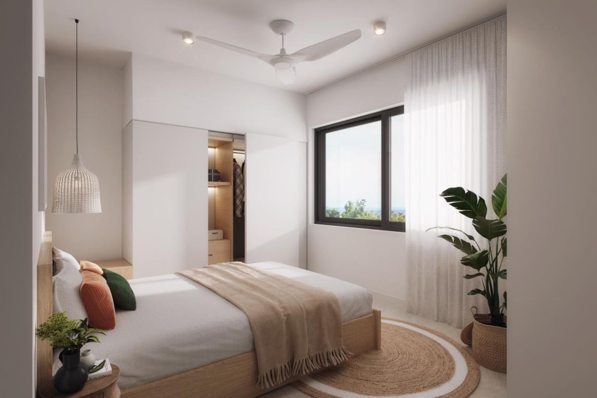 A modern, well-lit bedroom featuring built-in floor-to-ceiling wardrobes, a ceiling fan, and large windows with natural light.