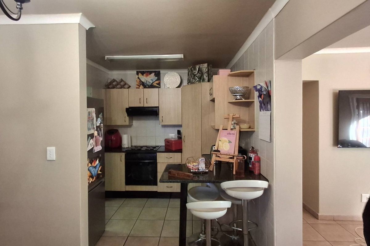 A functional kitchen featuring built-in cabinetry, integrated oven and hob, and a breakfast bar, seamlessly connected to the adjacent living area.