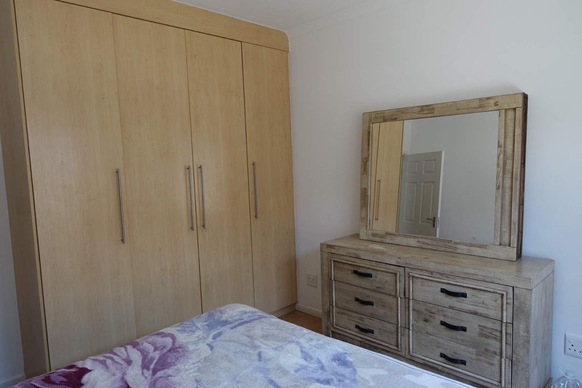 A bedroom featuring built-in light wood cabinetry with modern handles, providing ample storage space.